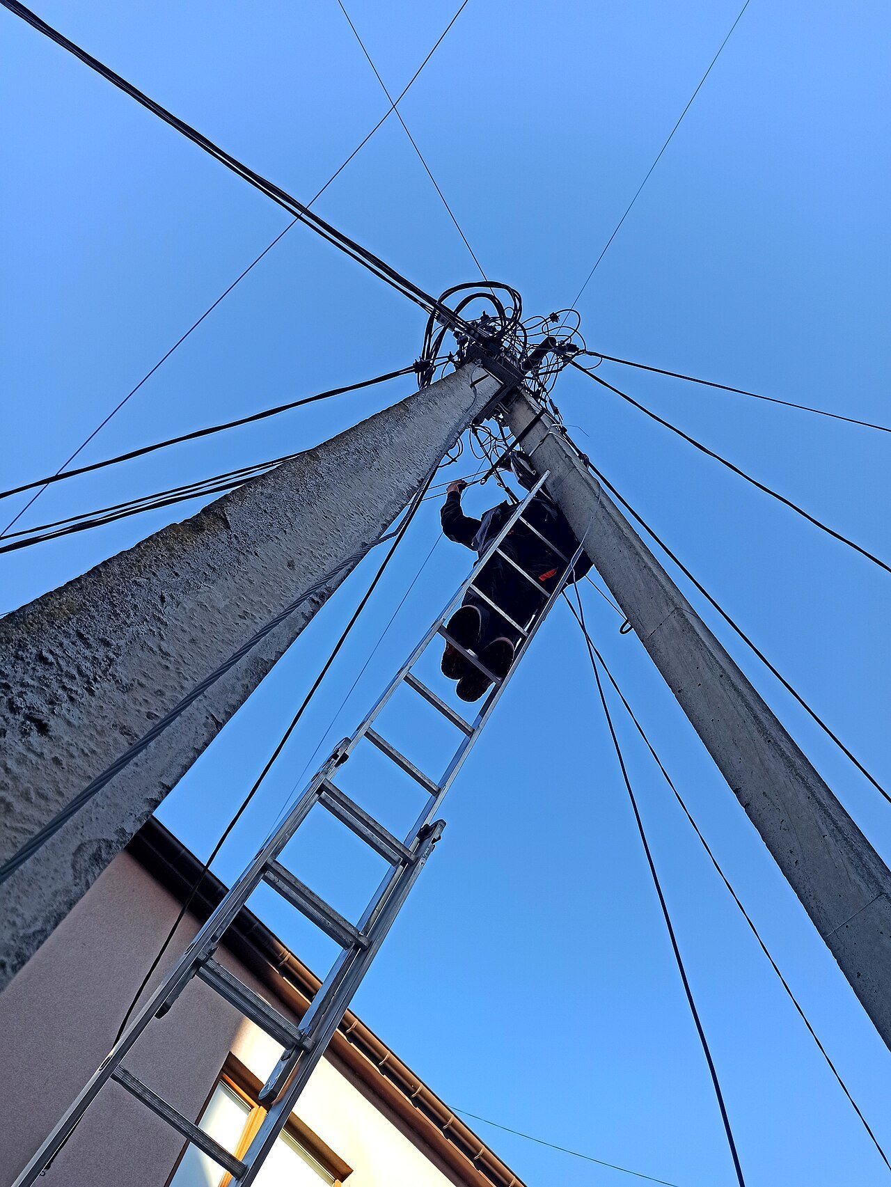 Telecommunications technician installing fiber network equipment on a utility pole